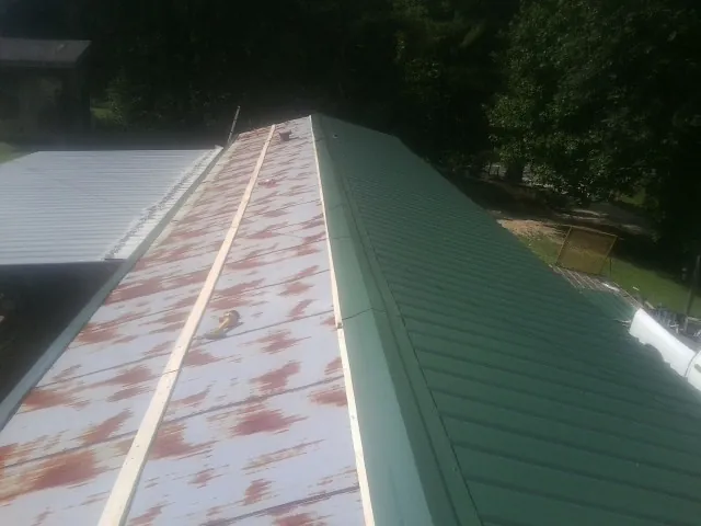 Old rusted panels beside newly installed green metal roofing — Wind Damage Roof Repair by Roofing Brothers in New Windsor