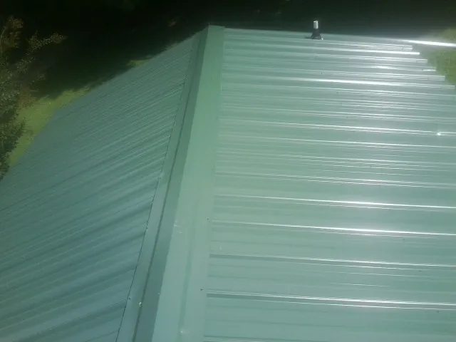 New green metal panels meeting at the ridge of a roof — Flat Roof Repair work by our crew in New Windsor