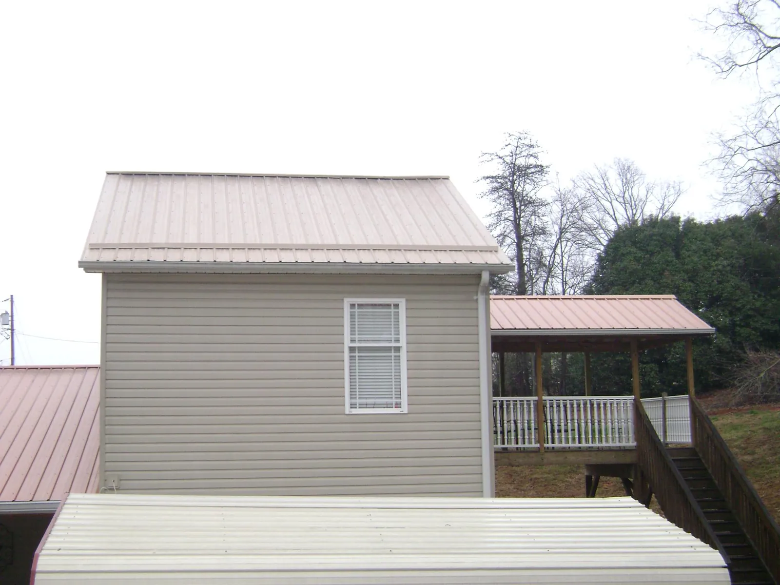 Tan metal roofs on a two story addition and attached porch, from a Roof Replacement job in New Windsor